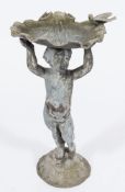 A lead bird bath: in the form of a putto supporting a clam shell above his head,