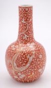 A Chinese iron-red and gilt bottle vase: painted with phoenix in flight on a ground of scrolling