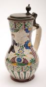 A German pewter mounted polychrome faience jug: of baluster form, the cover with ball thumb piece,