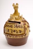 A slip decorated pottery money box: of dome shaped form surmounted with a mother hen surrounded by