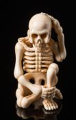 A Japanese ivory okimono: Meiji period (1864-1912), carved in the form of a seated human skeleton,