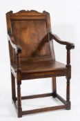An early 18th Century oak open armchair:, the moulded panel back with shaped fret cut cresting,