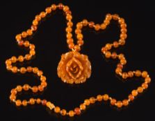 An amber bead single-string necklace: suspending an amber coloured carved flower pendant,