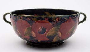 A Moorcroft pottery two handled bowl: of circular form tube lined in the Pomegranate pattern in red,