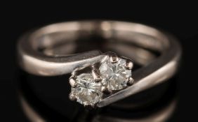 An 18ct white gold and diamond two stone cross-over ring: with circular,