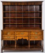 A late 18th/early 19th Century oak dresser:, the shelved superstructure with a moulded cornice,