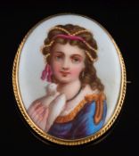 An enamelled porcelain panel brooch: depicting a young woman holding a dove in a 9ct gold frame,
