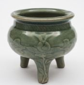 A Chinese celadon glazed tripod censer: of circular form on peg feet each with a raised flower