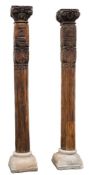 A pair of Indian carved wood cylindrical reeded columns: with foliate scroll and beaded capitals