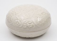 A Chinese porcelain box and cover: of circular form moulded in low relief with scrolling foliage,