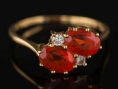 An 18ct gold, fire opal and diamond four-stone ring: the two oval fire opals between small,