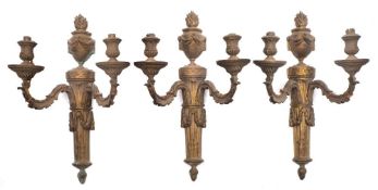 A set of three gilt metal twin-branch wall lights: each backplate with flaming urn and garland