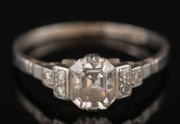 A platinum and diamond ring: with central step-cut diamond 6.1mm long x 5.5mm wide x 3.