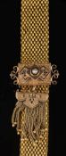 A late 19th/early 20th century gold and black enamelled mesh-link jarretiere: with tassel drop,