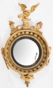 A Regency carved giltwood and gesso circular convex girandole wall mirror: surmounted by a figure