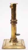 An early 18th century brass ejector candlestick: the plain nozzle and stem with hooked lip and