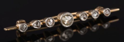 A rose diamond mounted bar brooch: with seven graduated stones in millegrain settings.