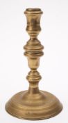 A late 17th century brass candlestick: with urn shaped nozzle on a knopped stem,