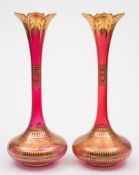 A pair of large Bohemian ruby stained and gilt vases: with slender necks and petal shaped rims,