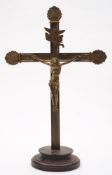 A late 19th century gilt brass crucifix: mounted in an ebonised circular plinth base, 62cm.