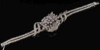 A diamond mounted bracelet: of stylised ribbon design with a central informal cluster of round,