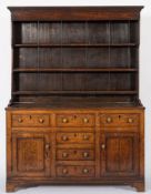An early 19th Century oak dresser:, the shelved superstructure with a moulded cornice,
