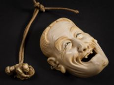 A Japanese carved ivory miniature mask: of a laughing man with open mouth and only two teeth,