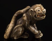 A Japanese carved ivory netsuke of a recumbent warthog: with inset eyes, signed, Meiji period, 4.
