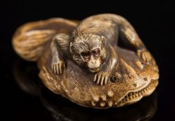 A Japanese carved ivory netsuke of a monkey soothing the god of earthquakes 'Namazu: signed