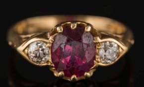 A gold, ruby and diamond three-stone ring: the cushion shaped ruby approximately 7.5mm long x 6.