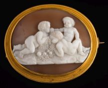 A mid/late 19th century gold and oval shell cameo brooch: depicting three recumbent putti feasting