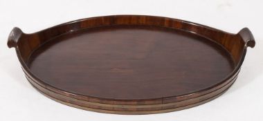 An 18th century mahogany and brass bound oval twin-handled tray:, having scroll handles,
