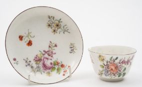 A Chelsea teabowl and saucer: painted with scattered floral sprays and sprigs within brown line