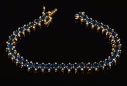 A sapphire and diamond line bracelet: with 40 oval sapphires each approximately 4.2mm long, 17.