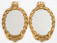 A pair of 19th century carved giltwood and gesso oval mirrors: with husk and palmette scroll