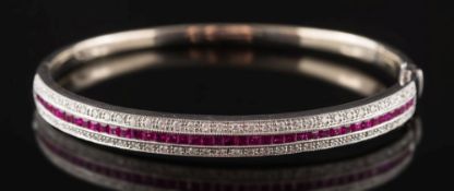 A ruby and diamond mounted hinged bangle: with central row of calibre-cut rubies estimated to weigh