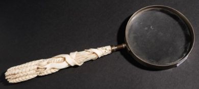 A 19th century magnifying glass: the ivory handle carved in the form of a wheatsheaf, 29cm.long.