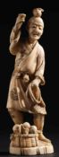 A Japanese carved ivory okimono: of a peasant holding a rope, with a basket of fruit at his feet,