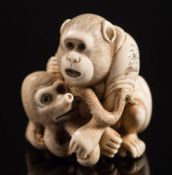 A Japanese carved ivory netsuke, depicting a monkey holding a young octopus: both with inset eyes,