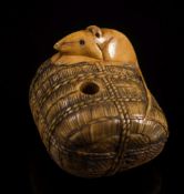 A Japanese carved ivory netsuke of a rat seated on a rope bound bale: with an articulated serpent's