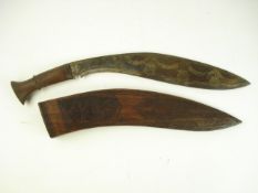 A kukri of traditional form with gilt decorated blade in carved wooden scabbard:, 50cm long..