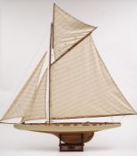 A model sailing yacht:, fully rigged and set sails over a planked deck with helm detailed fittings,