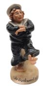 A Continental bisque porcelain humorous figure of a sailor: modelled barefoot in uniform and