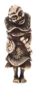 A Japanese carved bone netsuke: of a man wearing a large collar and holding a staff and bag,