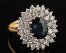 An 18ct gold, sapphire and diamond oval cluster ring: the central oval sapphire approximately 9.