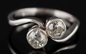 A diamond two-stone cross-over ring: millegrain set with round brilliant,
