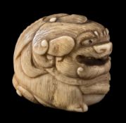 A Japanese carved ivory netsuke: of a mythical beast with a small loose ball in it's open mouth,