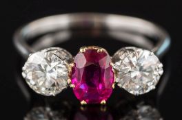 A ruby and diamond three-stone ring: the oval ruby approximately 7.2mm long x 5.3mm wide x 2.