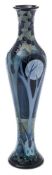 A Moorcroft pottery vase: of slender baluster form tube lined in the Broomy Wood pattern after the