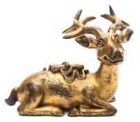 A Chinese gilt bronze figure: of a recumbent stag bearing bound scrolls upon it's back,
